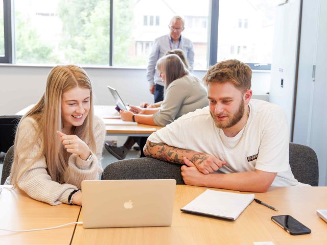 young woman and young man in classroom on laptop